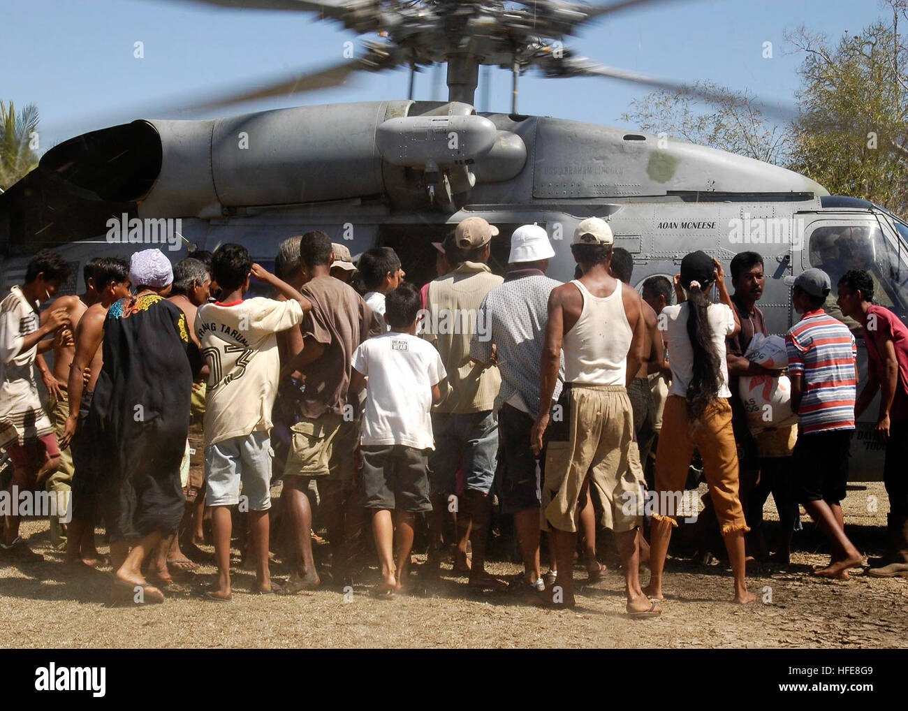 050118-N-4166B-050 lit bébé Daerah, Sumatra, Indonésie (janv. 18, 2005) Ð personnel local se réunir autour d'un Marine américain SH-60F Seahawk affectés à l'Escadron d'hélicoptères anti-sous-deux (HS-2) tout en offrant de la nourriture, de l'eau, et de fournitures médicales au village. Membres de l'Organisation des Nations Unies (ONU) - Organisation mondiale de la Santé (OMS), l'équipe d'évaluation en ce moment d'un séjour à bord du USS ABRAHAM LINCOLN (CVN 72), sont en train d'effectuer des sondages dans la région d'Aceh, à Sumatra pour déterminer les besoins des populations déplacées par le tsunami qui a frappé l'Asie du Sud le 26 décembre faisant plus de 150 000 peop Banque D'Images