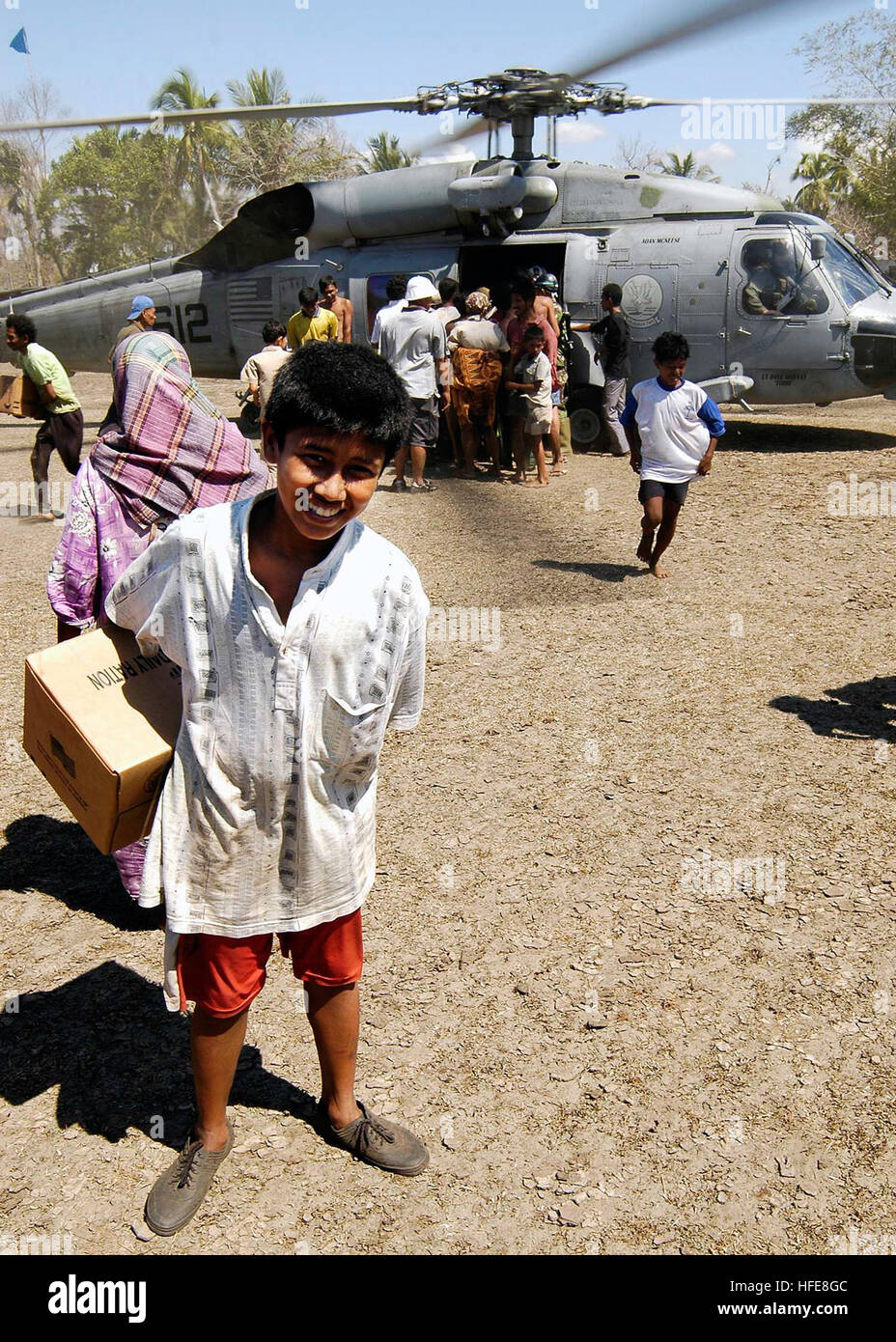 050118-N-4166B-067 lit bébé Daerah, Sumatra, Indonésie (janv. 18, 2005) Ð personnel local se réunir autour d'un Marine américain SH-60F Seahawk affectés à l'Escadron d'hélicoptères anti-sous-deux (HS-2) tout en offrant de la nourriture, de l'eau, et de fournitures médicales au village. Membres de l'Organisation des Nations Unies (ONU) - Organisation mondiale de la Santé (OMS), l'équipe d'évaluation en ce moment d'un séjour à bord du USS ABRAHAM LINCOLN (CVN 72), sont en train d'effectuer des sondages dans la région d'Aceh, à Sumatra pour déterminer les besoins des populations déplacées par le tsunami qui a frappé l'Asie du Sud le 26 décembre faisant plus de 150 000 personnes Banque D'Images
