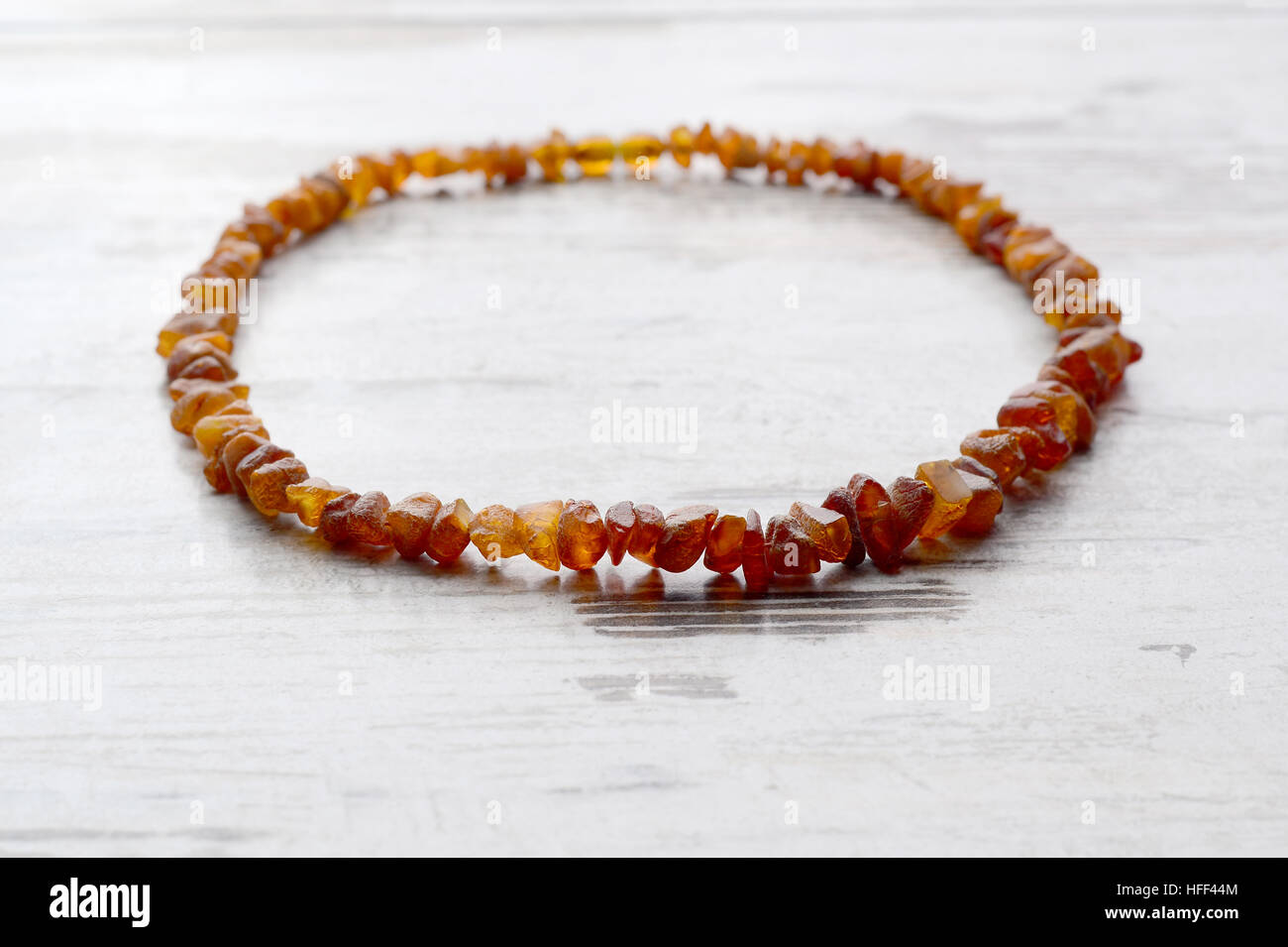 Collier ambre orange vif de matière première chaîne de perles sur un vieux fond de bois gris Banque D'Images