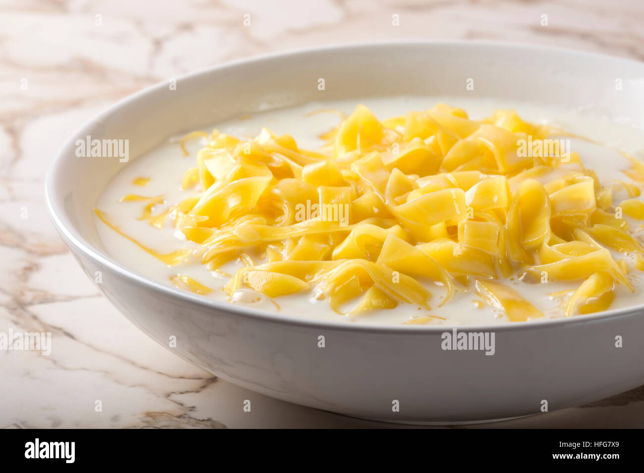 Les nouilles (tagliatelle) avec du lait et le sucre dans un bol en céramique blanche Banque D'Images
