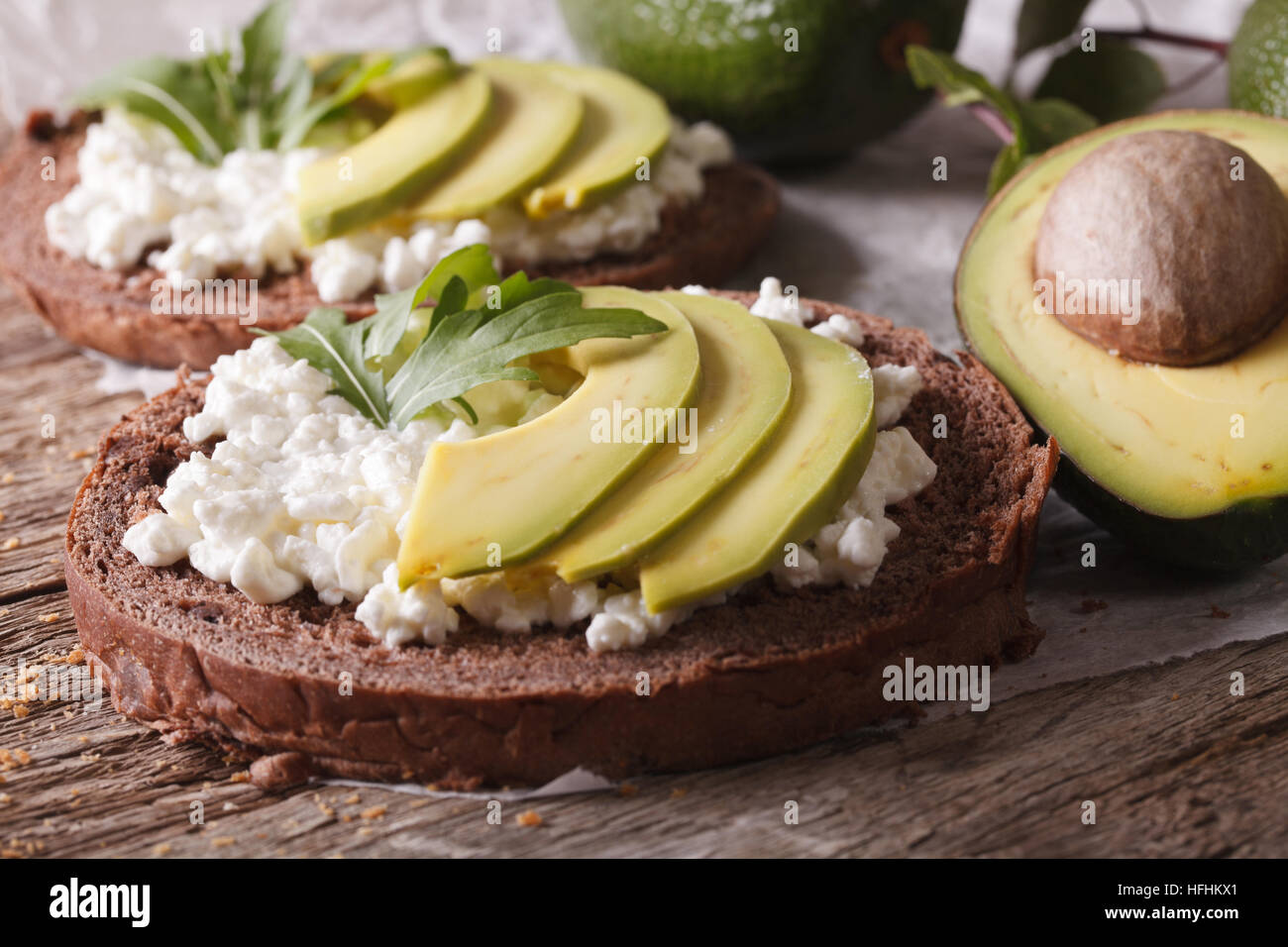 Sandwichs sains avec avocat, fromage à la crème et à la roquette sur la table horizontale. Banque D'Images