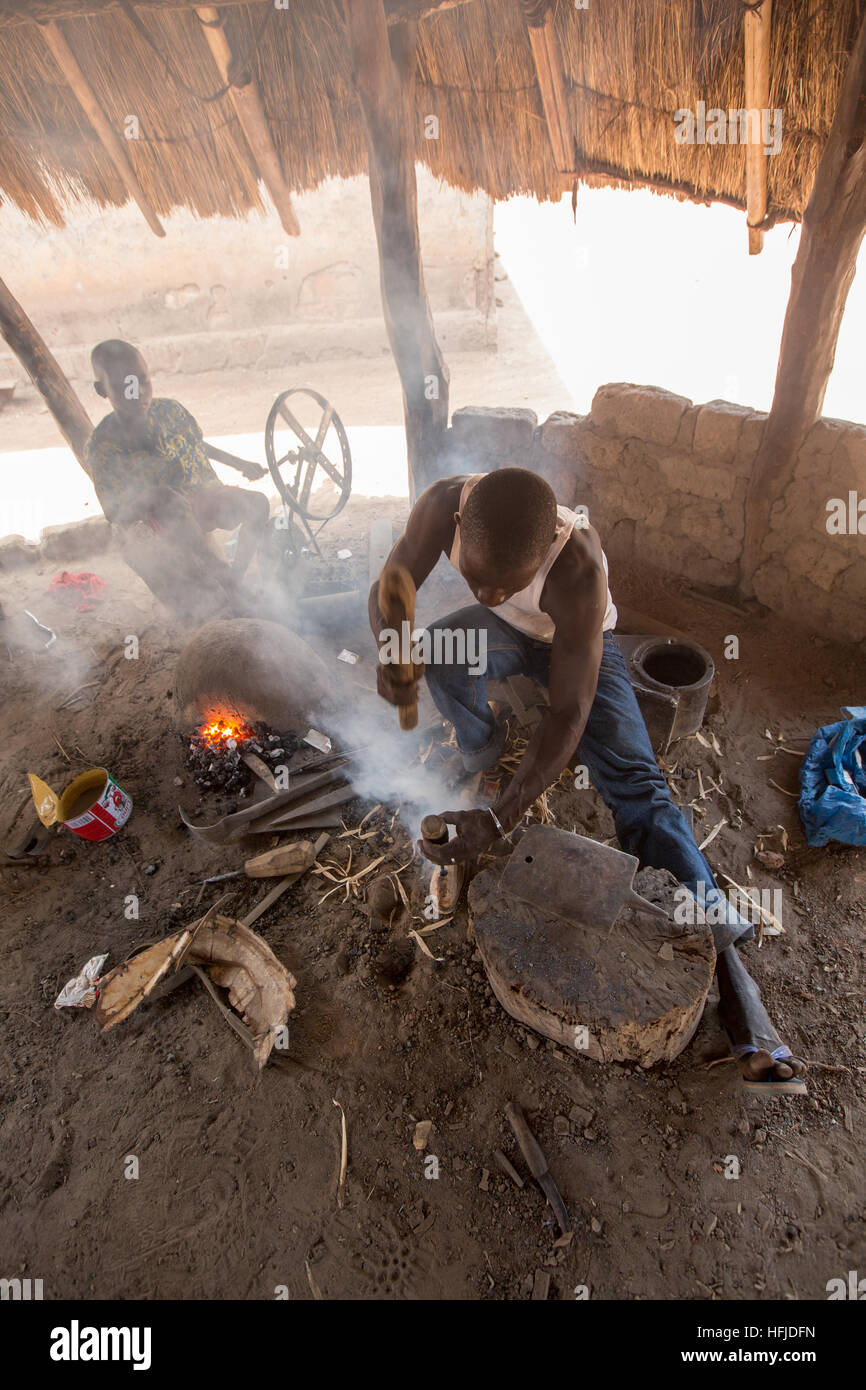 Kiniero, Guinée, le 30 avril 2015 : Mamady Camara, 35 ans, a été un forgeron depuis qu'il était un enfant, ici prendre une poignée pour une hache. Banque D'Images