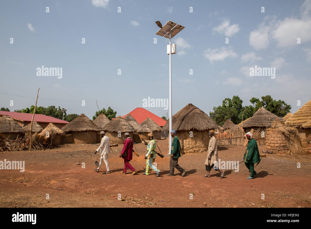 Gbderedou Baranama, Guinée, 2 mai 2015 ; un groupe de chasseurs du village avec leurs fusils à pied passé à énergie solaire nouvellement installé l'éclairage des rues. Banque D'Images