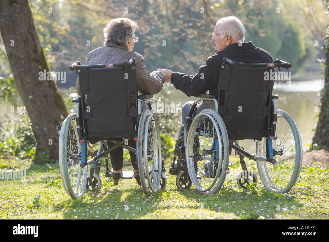 Couple de personnes âgées en fauteuil roulant, holding hands Banque D'Images