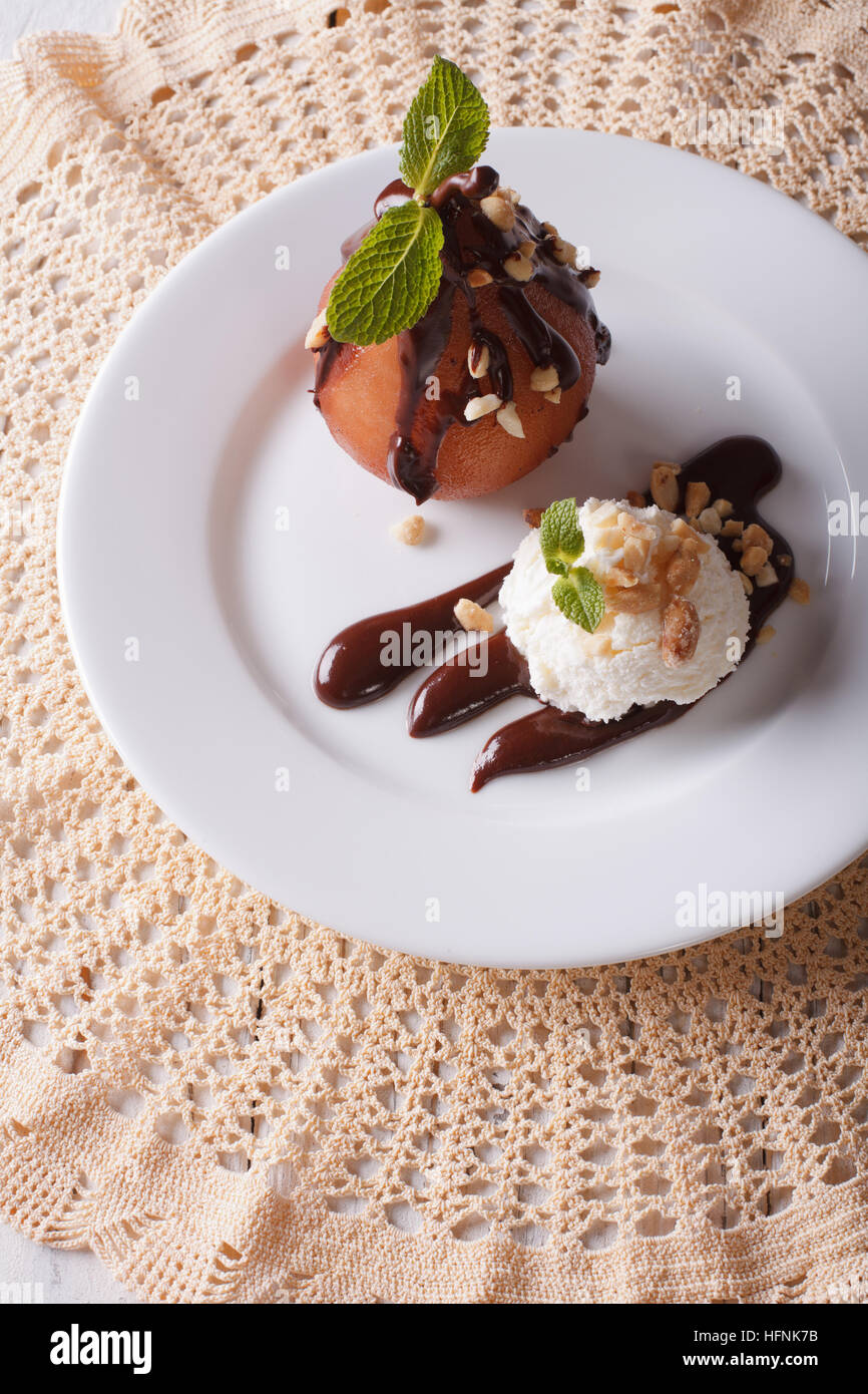 Poire pochée au chocolat et la crème glacée sur une assiette. vertical Vue de dessus Banque D'Images