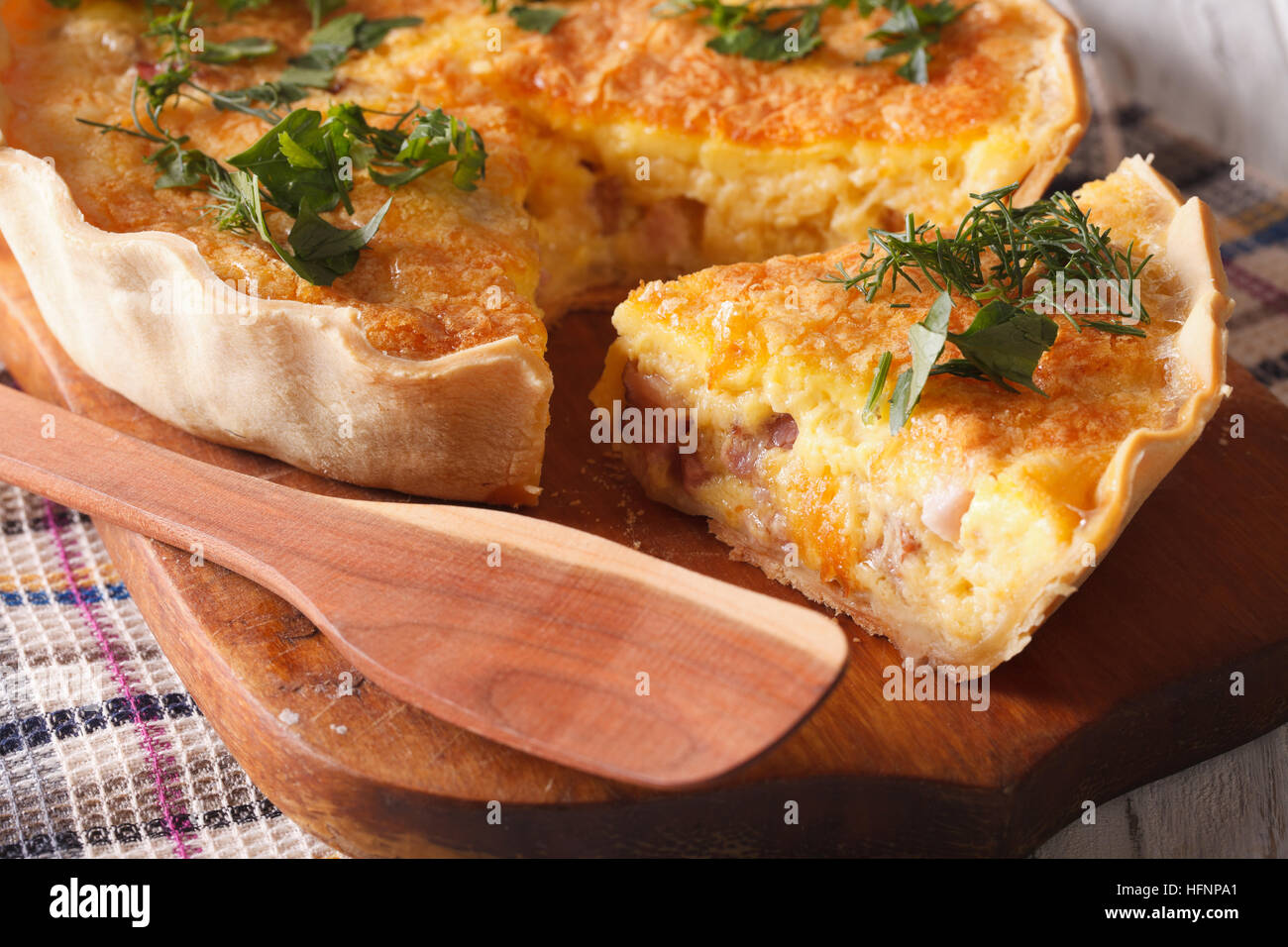 Quiche en tranches avec du fromage, des œufs et du bacon close-up sur une planche horizontale. Banque D'Images