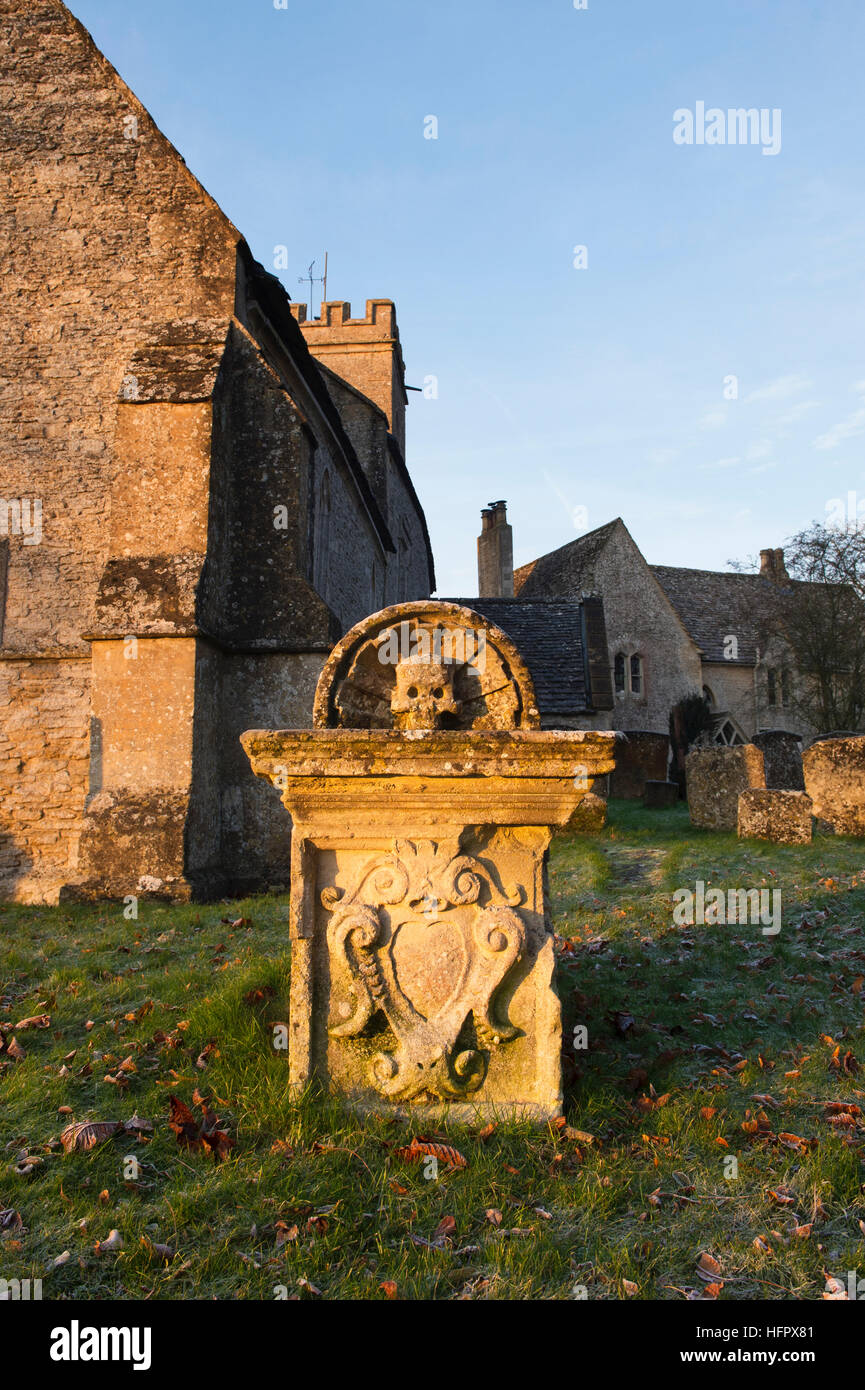 Église Saint Rood et tombe dans la lumière du soleil d'hiver tôt le matin. Shilton, Nr Burford, Cotswolds, Oxfordshire, Angleterre Banque D'Images