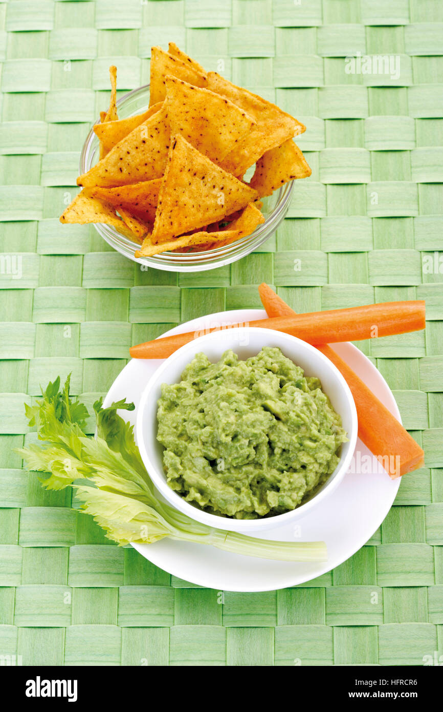 Nachos et guacamole d'avocat (DIP) garni de carottes et céleri Banque D'Images