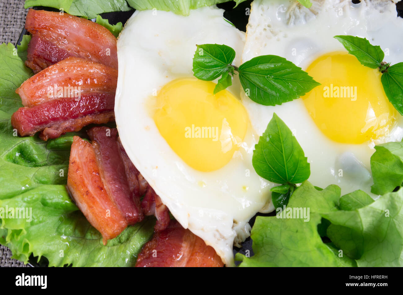 Top View close-up sur une plaque avec des œufs au plat et lard grillé aux herbes et laitue Banque D'Images