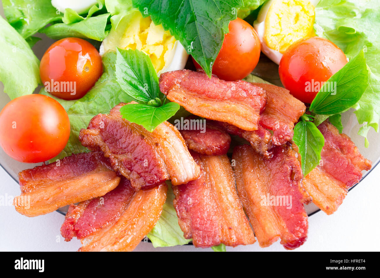 Vue de dessus d'un fragment d'un gros plan de la plaque avec laitue, tomates cerises, bacon, les herbes et les œufs durs avec une faible profondeur de foyer Banque D'Images