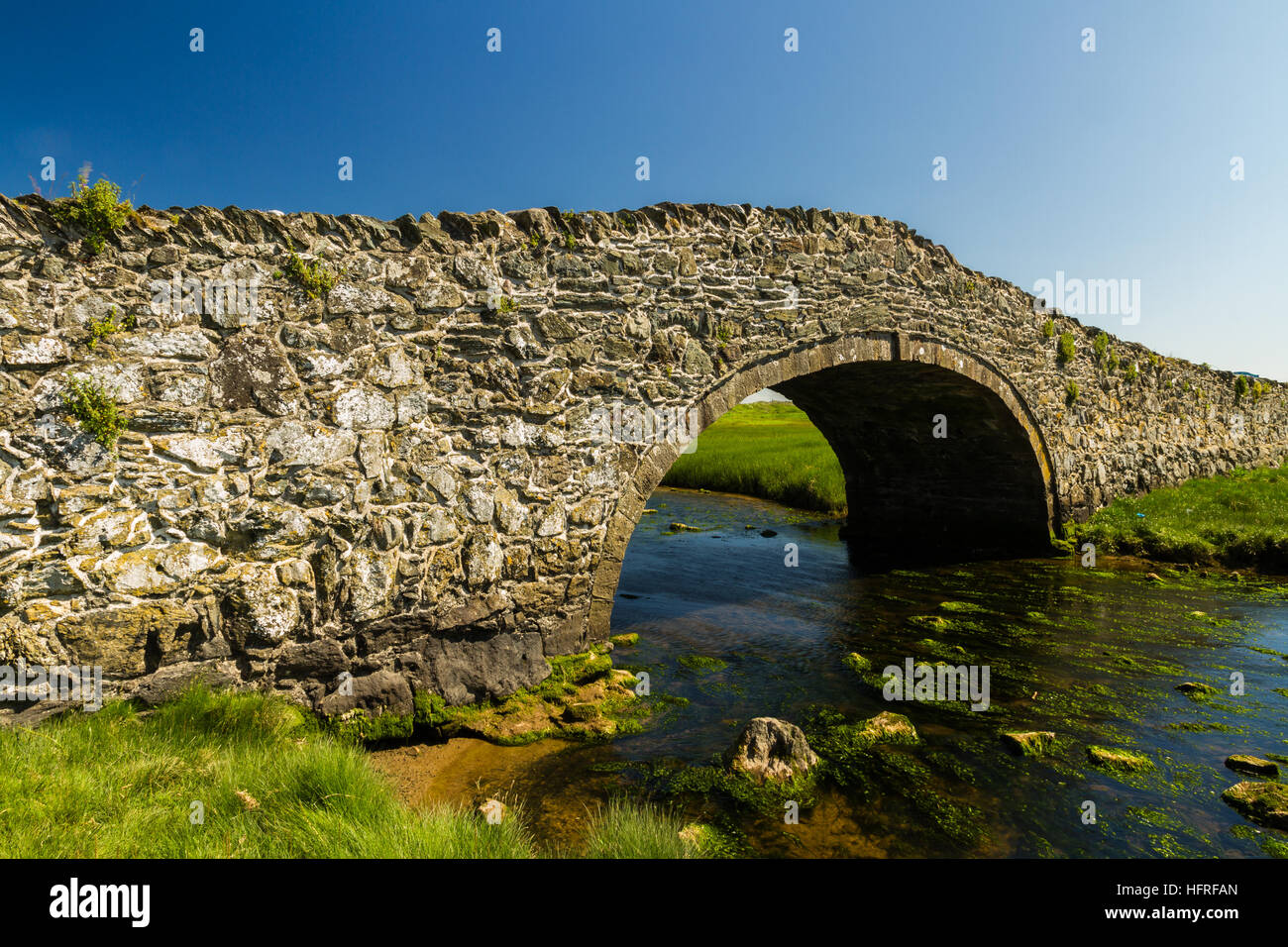Dix-huitième siècle en pierre pont arrière bosse, avec canal d'eau, la rivière, Ffraw et ciel bleu. Aberffraw, Anglesey, Pays de Galles, Royaume-Uni, Europe Banque D'Images
