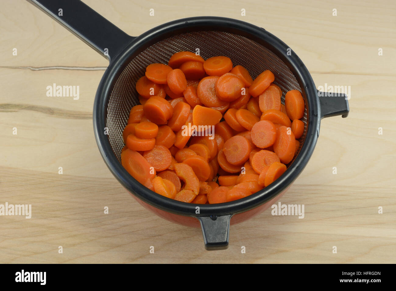 Tranches de carottes en conserve, rincés vidange de la crépine dans un bol pour retirer le sel Banque D'Images