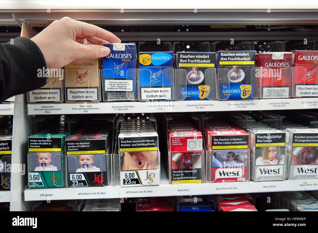 Des cigarettes dans un supermarché avec photos sur les paquets de cigarettes pour illustrer les dangers du tabagisme Banque D'Images