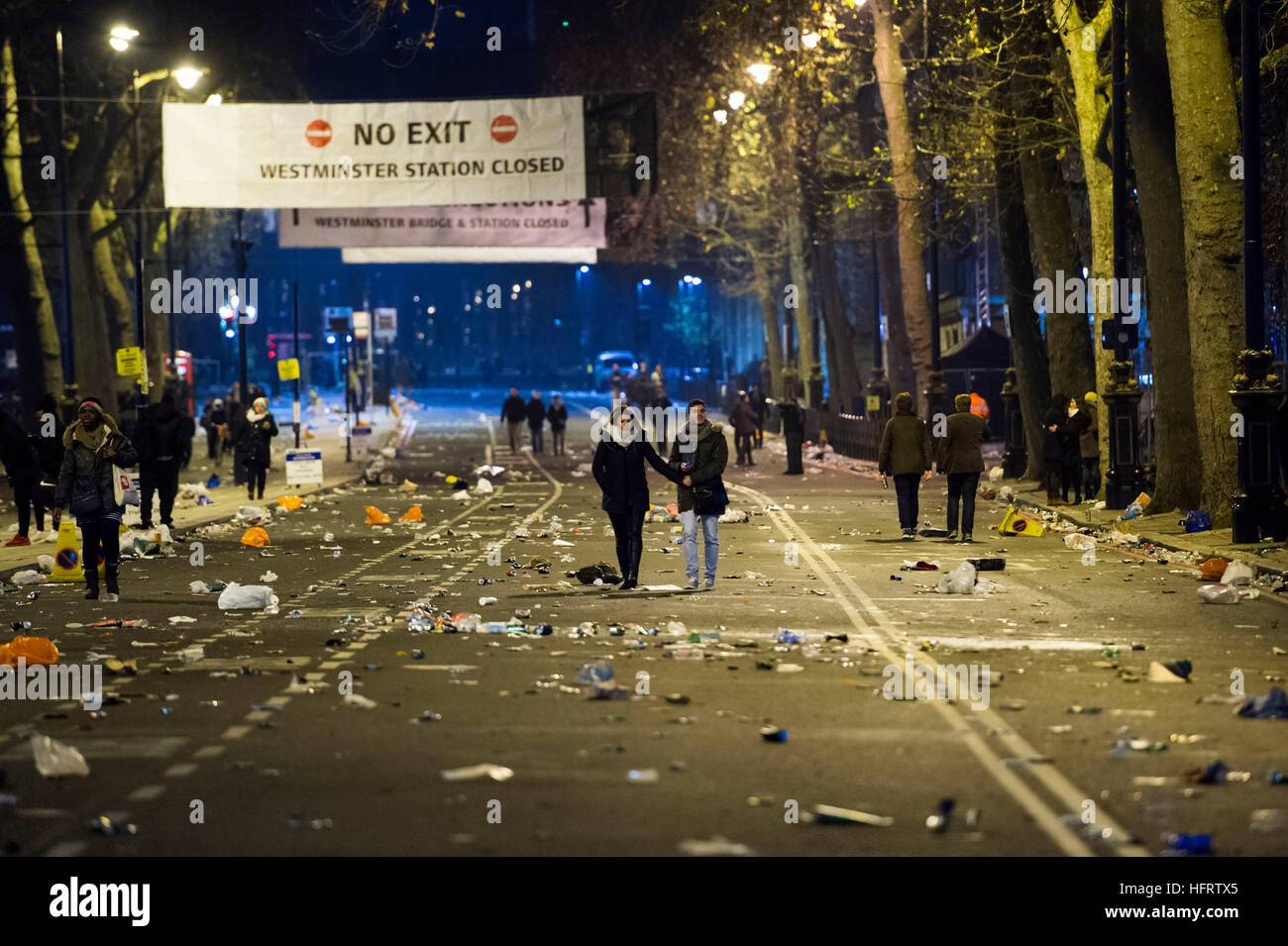 Un couple marche main dans la main passé des tas de déchets sur l'Albert Embankment, dans le centre de Londres après les foules s'en alla à la suite de la nouvelle année. Banque D'Images