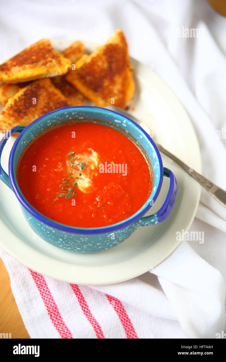 Bol de soupe à la tomate avec du thym frais et de crème fraîche et un sandwich au fromage grillé Banque D'Images