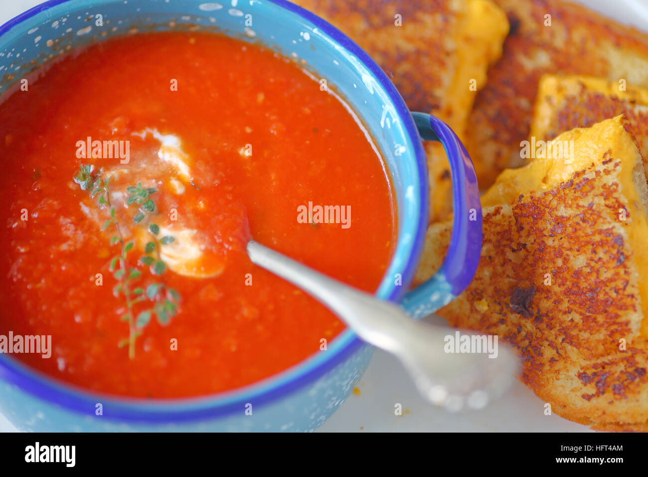 Soupe de tomate dans un bol de l'émaillerie avec un sandwich au fromage coupé en triangles Banque D'Images