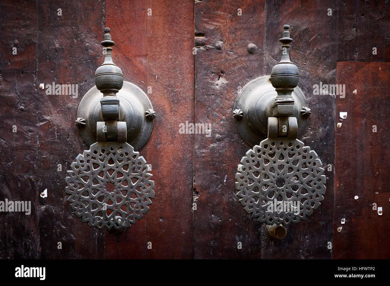 Des poignées de portes / portes en bois de heurtoirs sur la Bou Inania mosquée dans la médina de Fès, Maroc. Banque D'Images