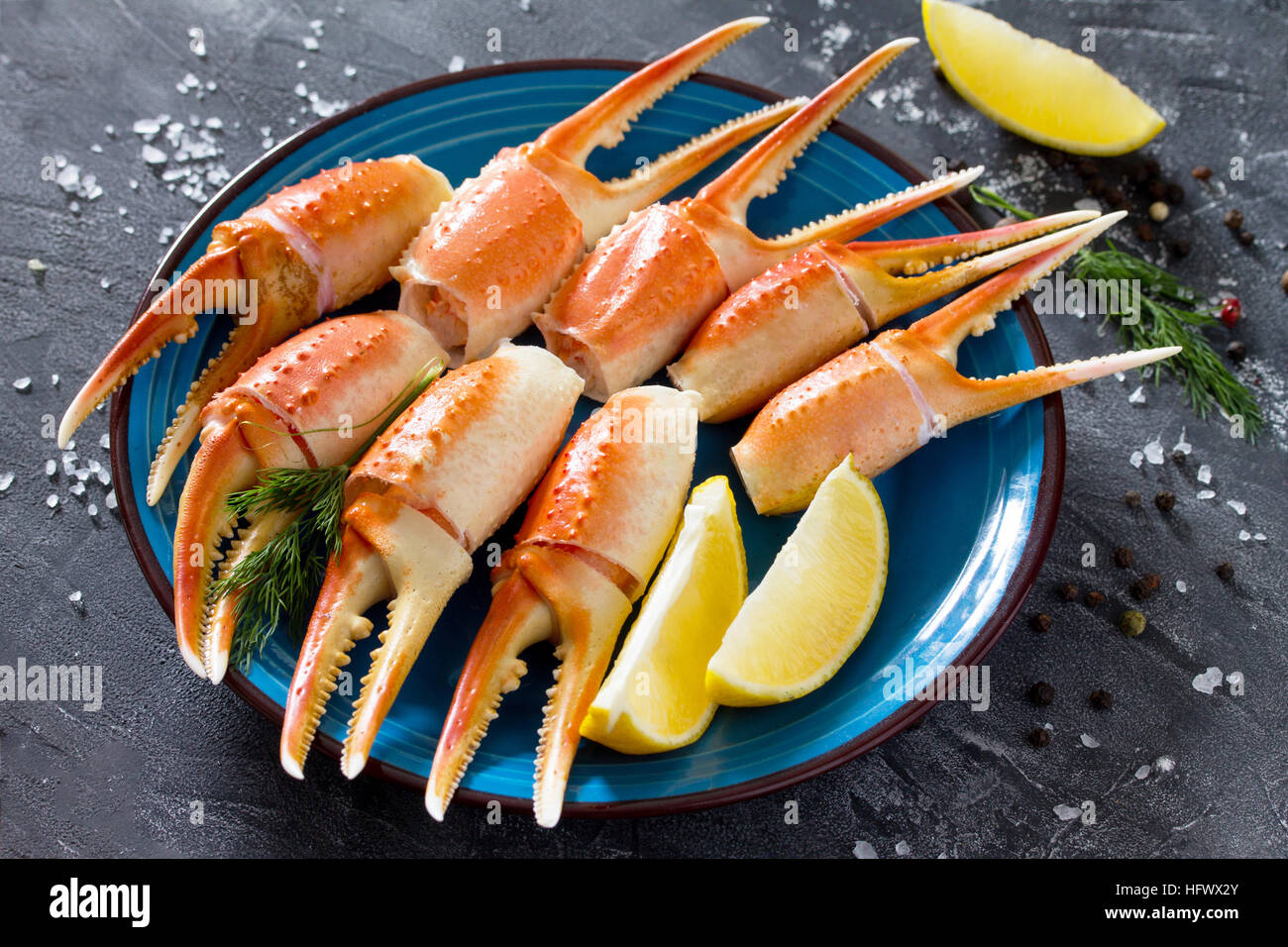 Pinces de crabe cuites avec du citron, sel de mer et poivre sur un fond en béton. Banque D'Images