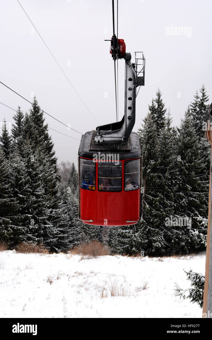 Cabine téléphérique rouge avec des pins et de la neige à la montagne l'arrière-plan Banque D'Images