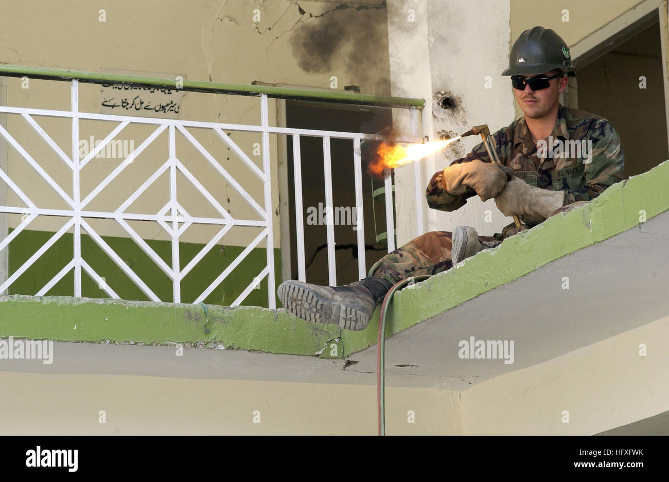 Travailleur de l'acier, Constructionman Casey Bon de Huntington, W.Va., allume une torche pour couper à travers garde-corps de l'école un condamné à être démolis à Muzaffarabad, Pakistan, le 9 novembre 2005. SWCR Casey bon est membre du Bataillon mobile de construction navale 74. Le gouvernement des États-Unis est de participer à une force multinationale de l'aide humanitaire et le soutien d'efforts menés par le Gouvernement pakistanais pour venir en aide aux victimes du séisme dévastateur qui a frappé la région le 8 octobre 2005. (U.S. Air Force photo par un membre de la 1re classe Barry Loo) US Navy 051109-F-2729G-007 de la marine américaine de l'acier Banque D'Images