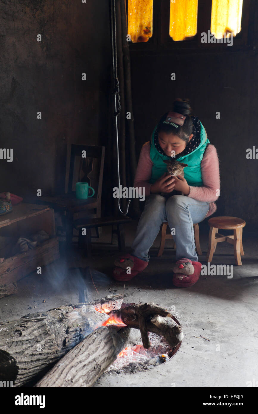 Une adolescente câlins son chat qu'elle s'assoit dans le salon de sa maison des parents près de l'incendie pour garder au chaud en hiver. Banque D'Images