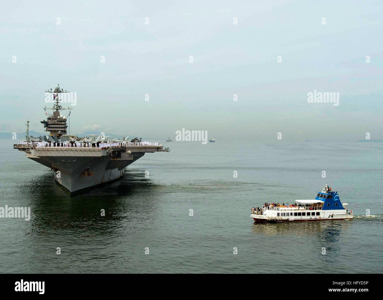 Un ferry transporte media pour documenter le porte-avions USS George  Washington ancre à mesure que le navire entre dans la baie de Manille pour  commencer un service de quatre jours au port.