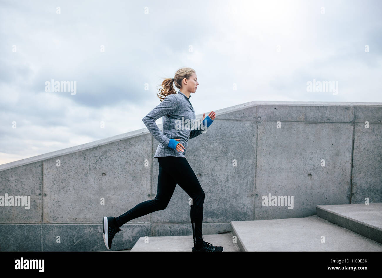 Vue de côté tourné de santé de la jeune femme en jogging. Les étapes d'escalade femelle à l'extérieur. Banque D'Images