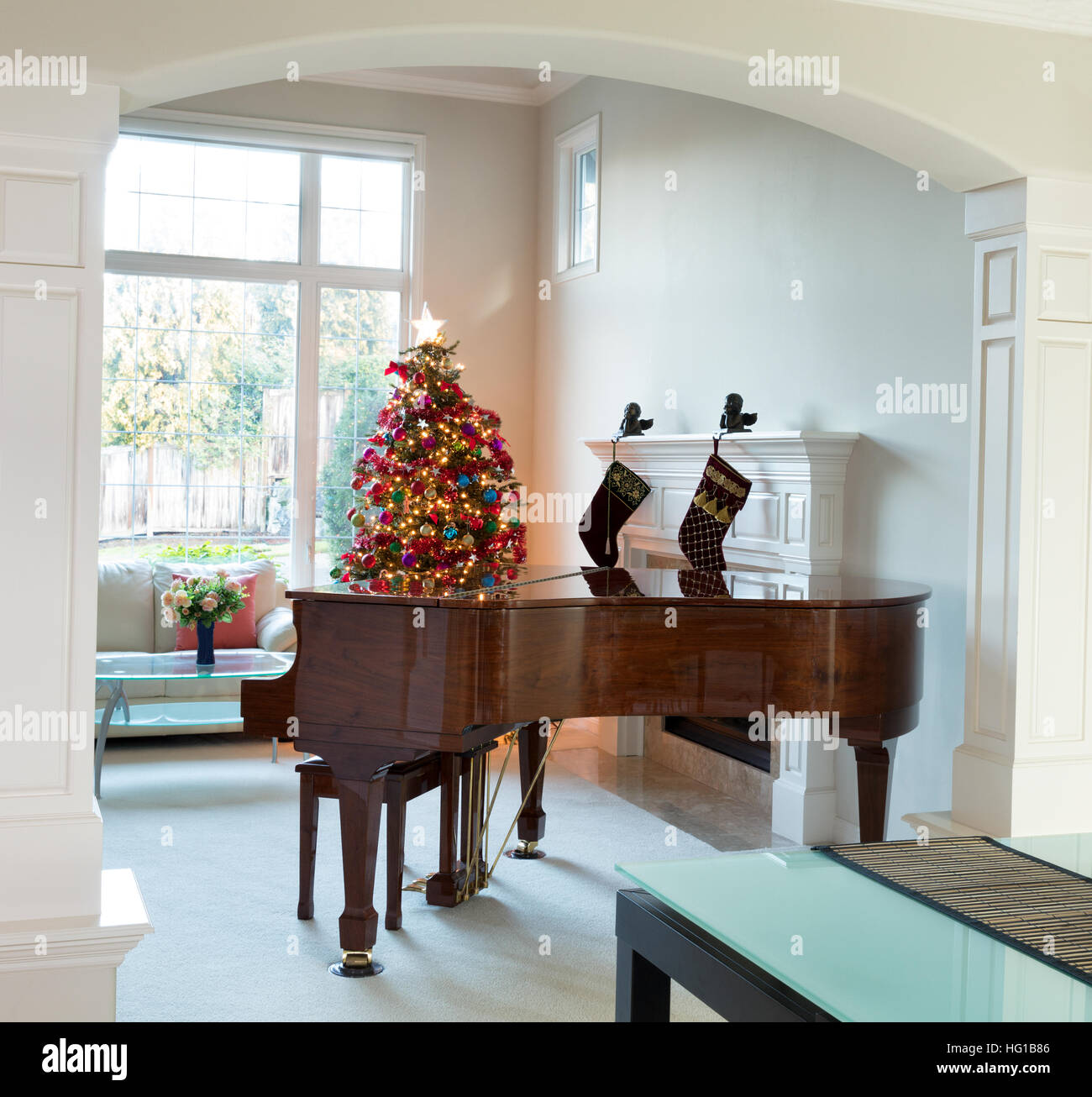 Entrée salon avec piano à queue, l'arbre de Noël décoré et grande fenêtre de jour en arrière-plan Banque D'Images