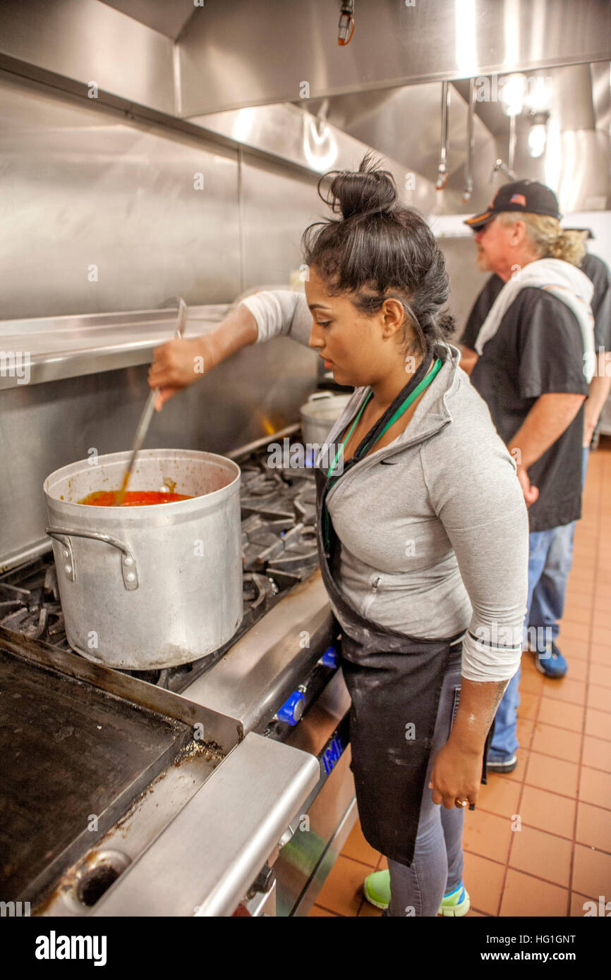 Un jeune volontaire suscite la soupe pour distribution aux familles nécessiteuses dans un entrepôt de la banque alimentaire de bienfaisance à Costa Mesa, CA. Banque D'Images