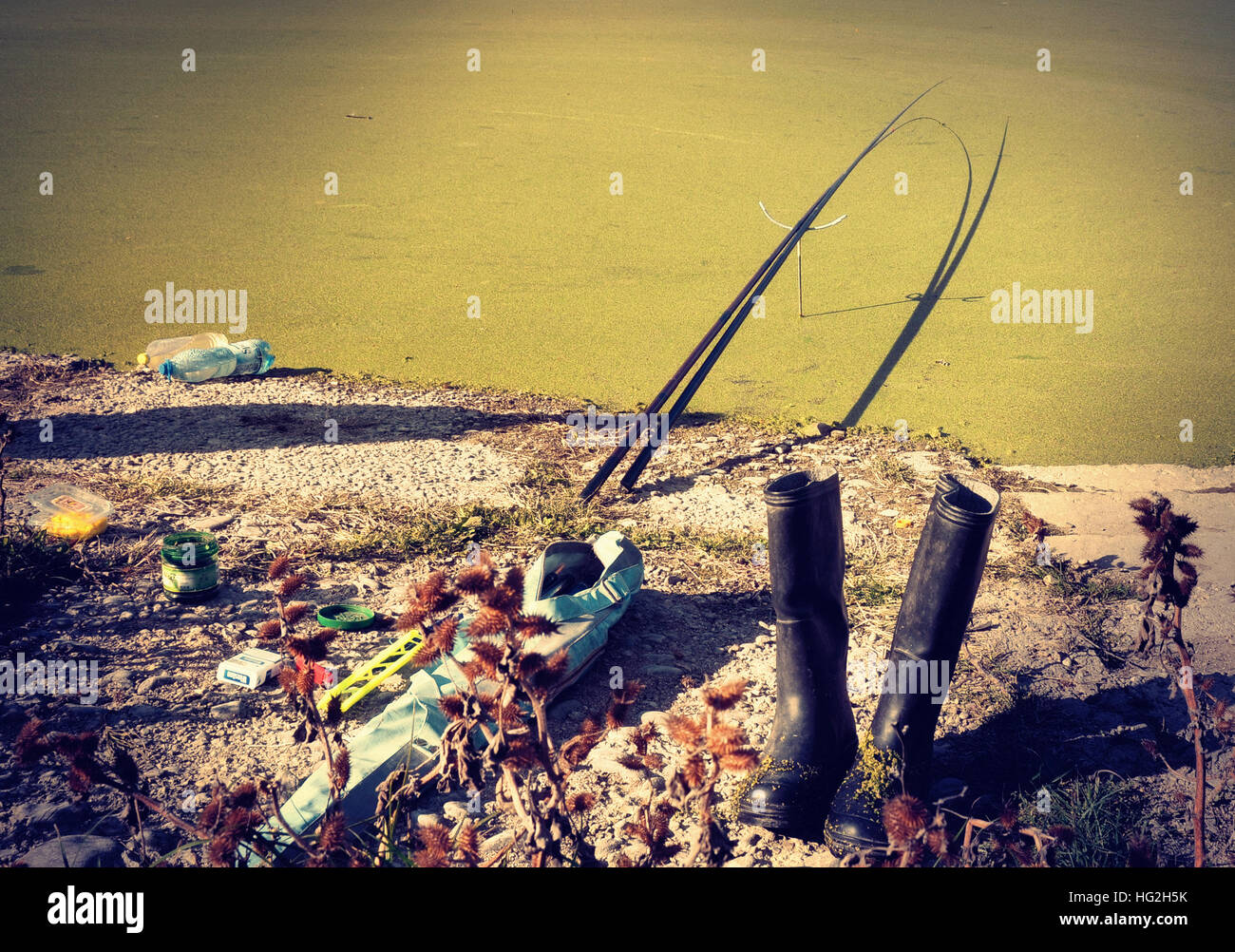 Les accessoires du pêcheur sont sur la rive d'un lac couverts de mousse, mais le pêcheur lui-même est manquante. Banque D'Images