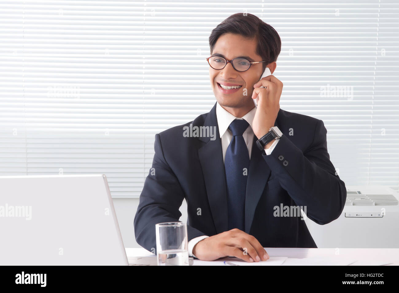 Heureux à la jeune homme professionnel de conversations au téléphone en chambre bureau Banque D'Images