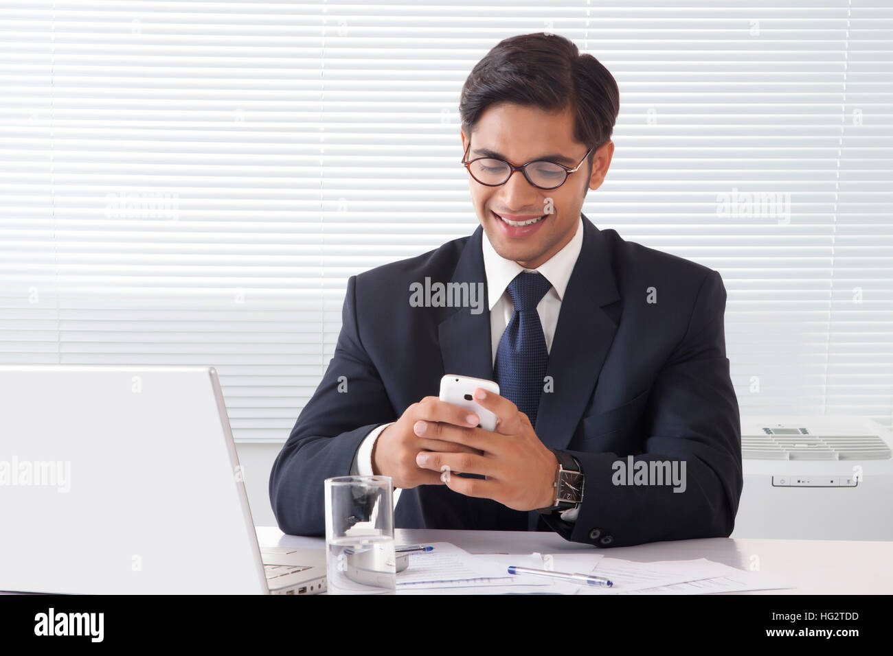 Heureux à la jeune homme professionnel l'exploitation de son téléphone mobile à Office 24 Banque D'Images