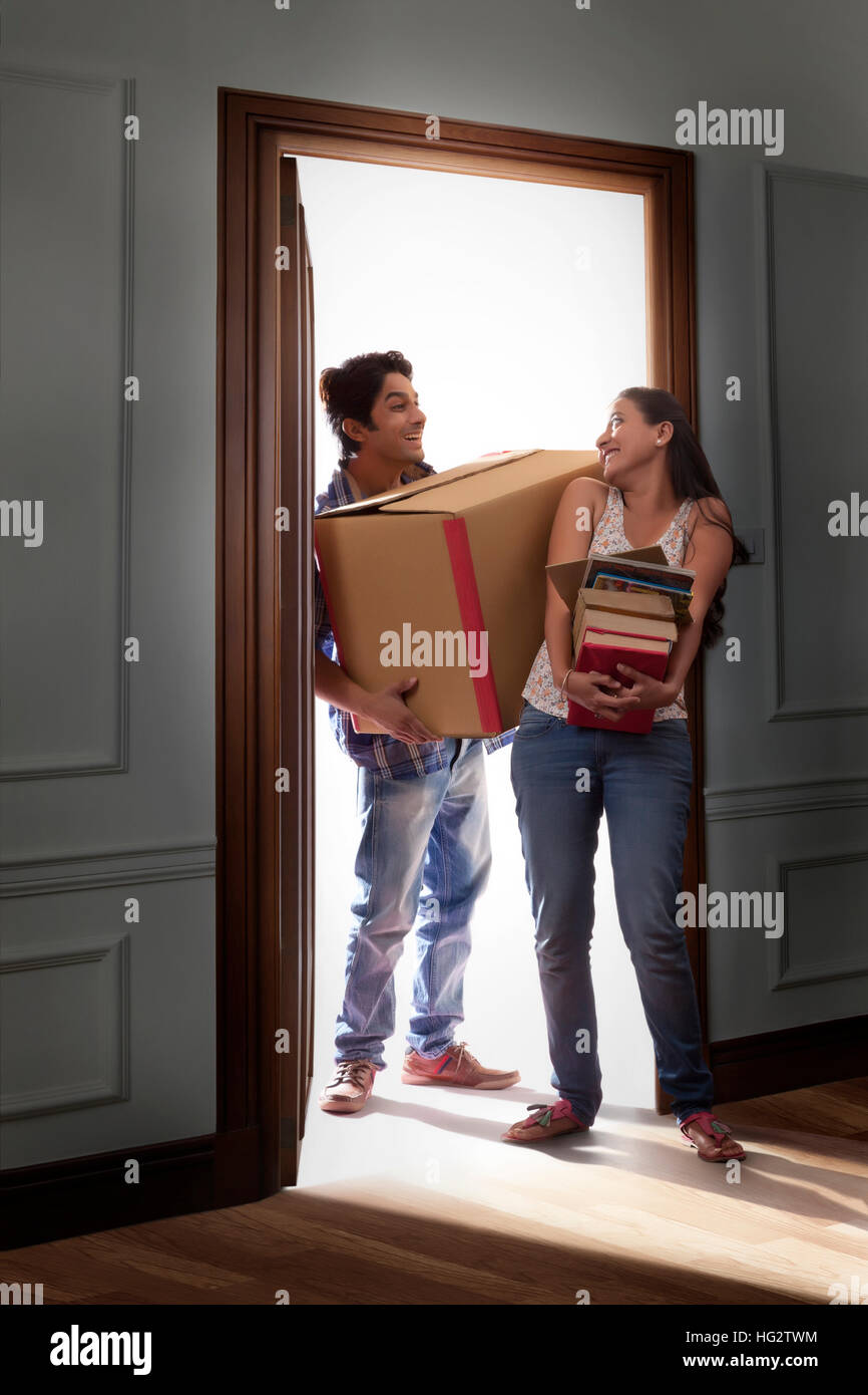 Young man carrying cardboard box avec femme tout en se déplaçant dans Banque D'Images