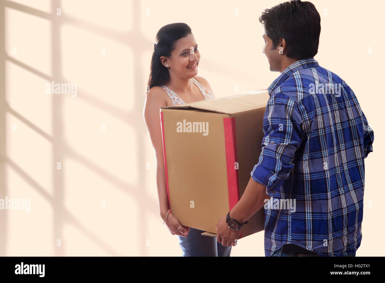 Young man carrying cardboard box avec femme tout en se déplaçant dans Banque D'Images