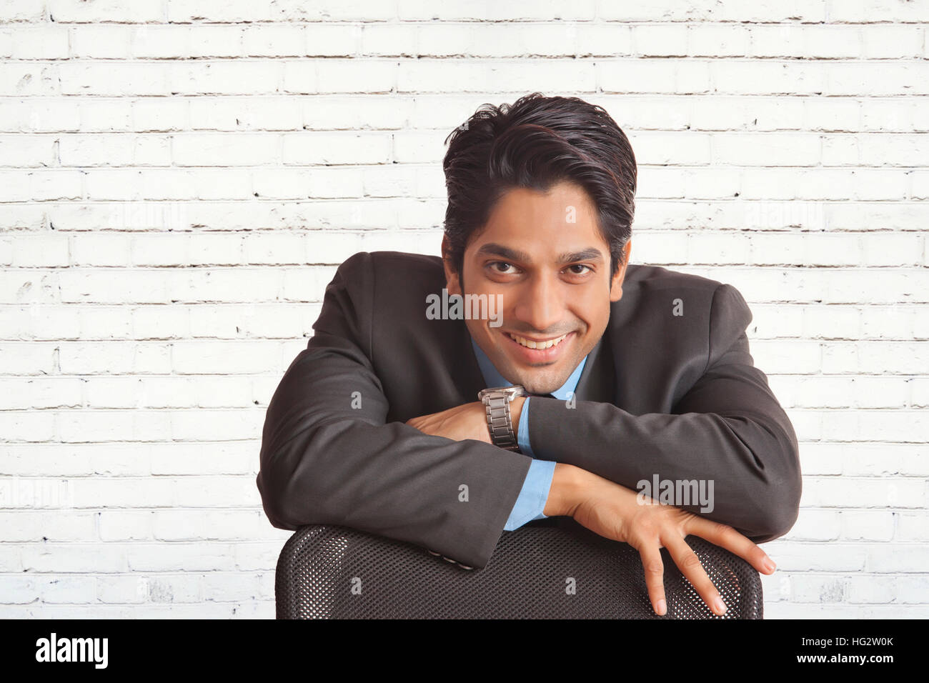 Happy businessman leaning on chair looking at camera Banque D'Images