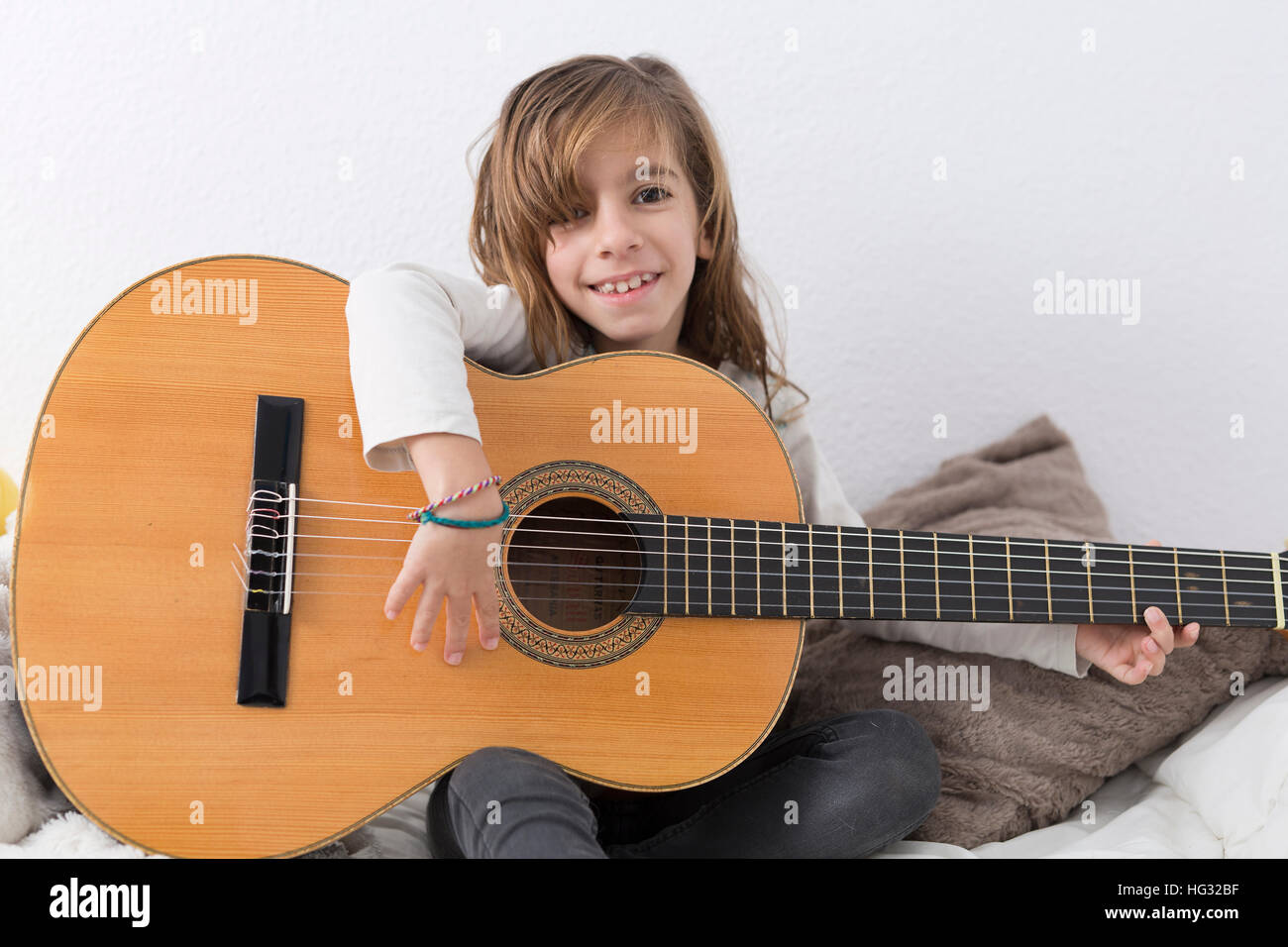 Petite fille apprendre à jouer de la guitare classique, assis sur son lit  Photo Stock - Alamy