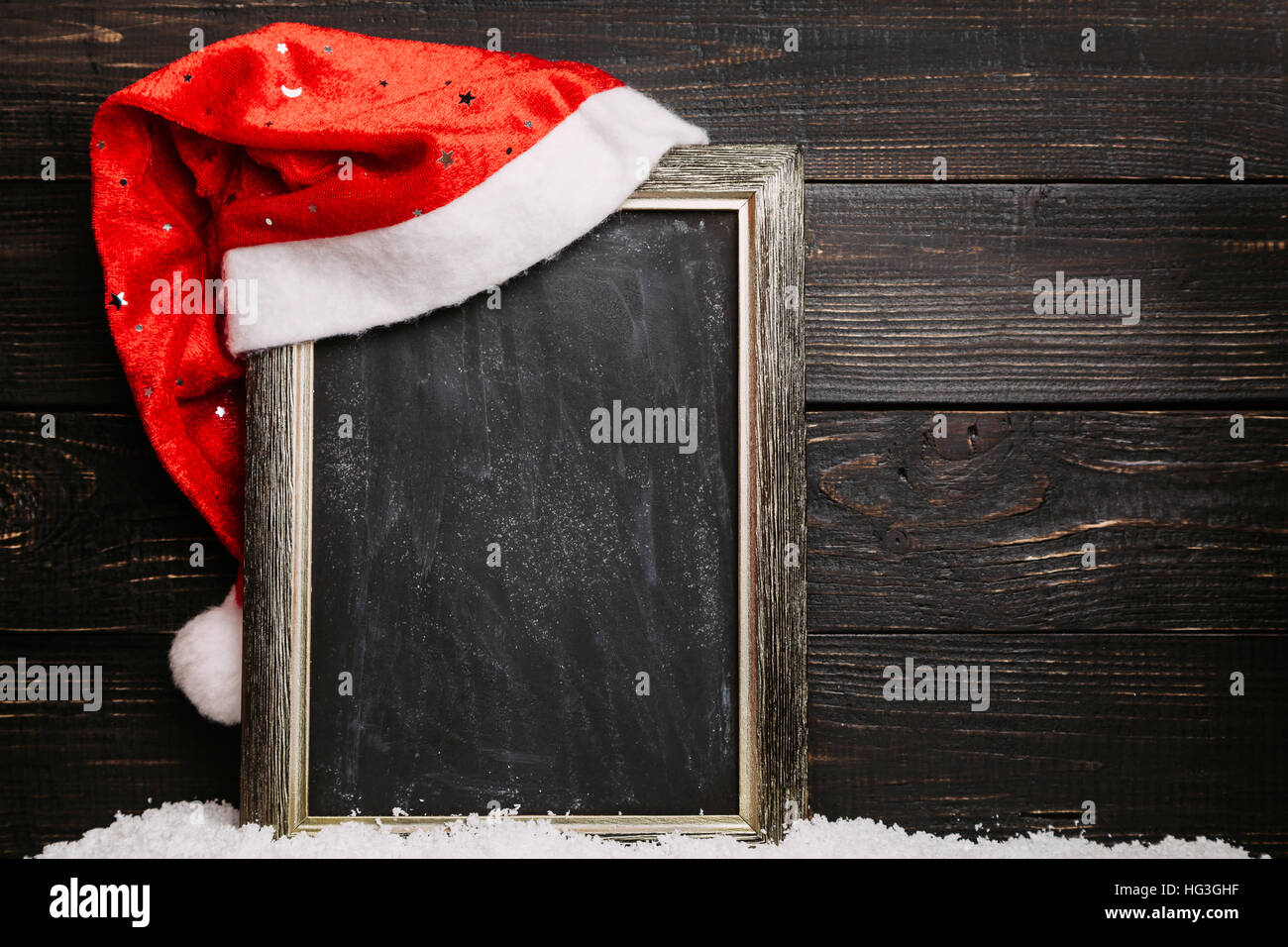 Santa hat rouge sur le tableau noir sale avec la neige. Châssis avec copyspace, fond de Noël Banque D'Images