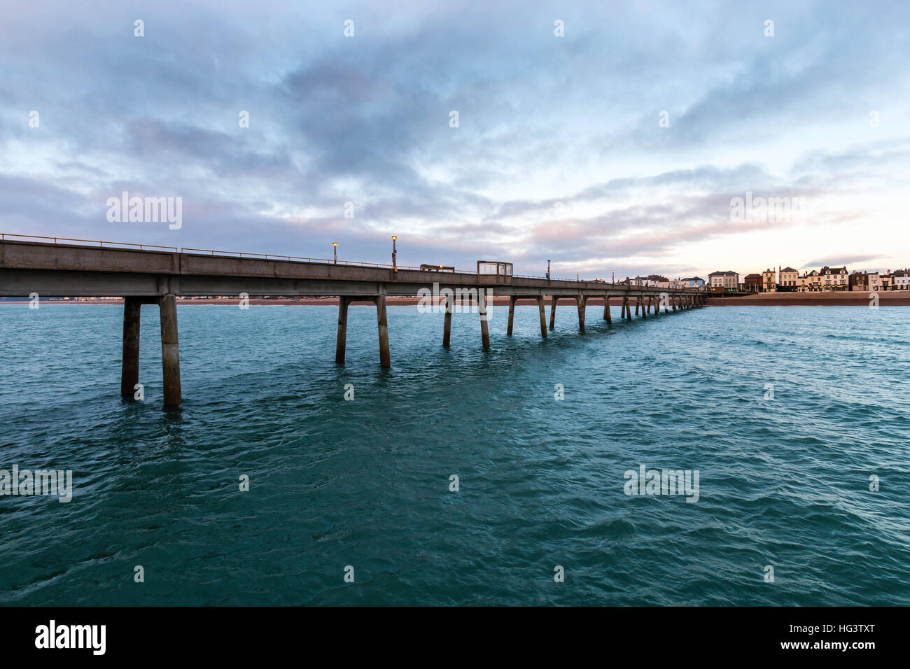 Jetée de Deal, dans le Kent en Angleterre. Jetée en béton construire dans les années 1950. Voir à partir de la fin de la jetée à la retour à la plage et de la ville. Dawn nuages sombres dans le ciel. Mer calme. Banque D'Images