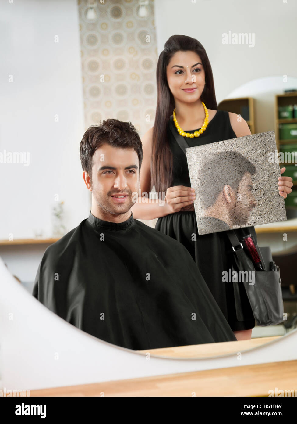 Client heureux en se regardant dans un miroir après avoir obtenu une coupe dans un salon de coiffure Banque D'Images