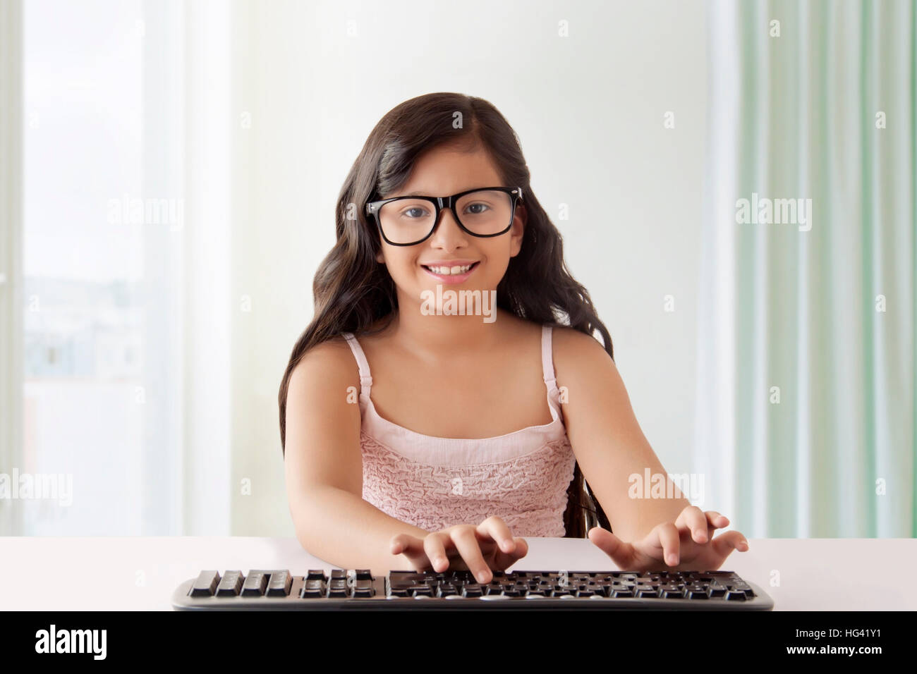 Fille avec de grandes lunettes noires de taper au clavier Banque D'Images