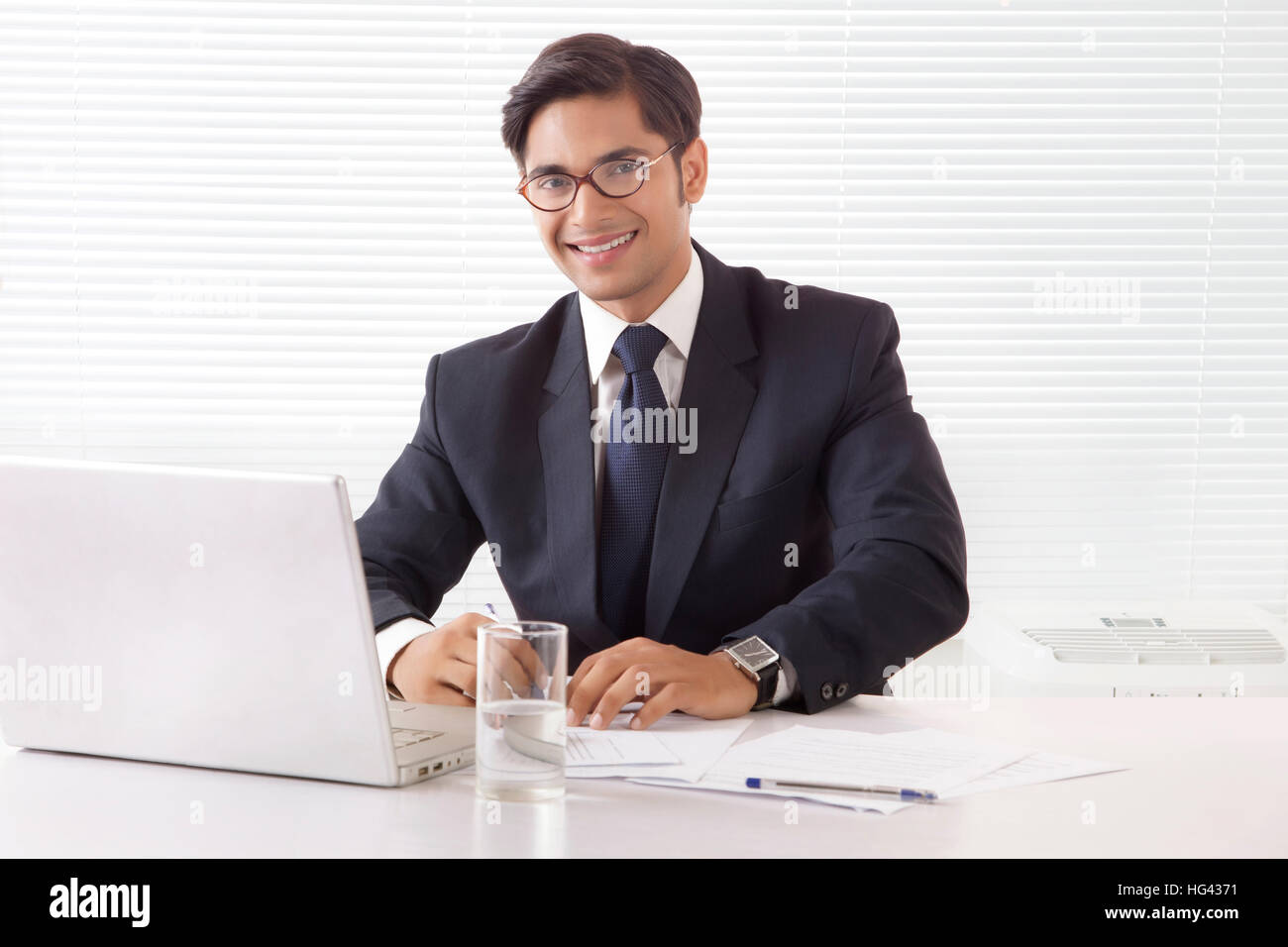 Les jeunes professionnels et souriant homme professionnel en bureau avec ordinateur portable sur la table Banque D'Images