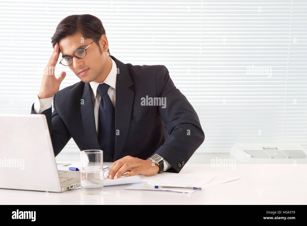 Jeune homme professionnel à la main tendue avec le front while looking at laptop computer in office Banque D'Images