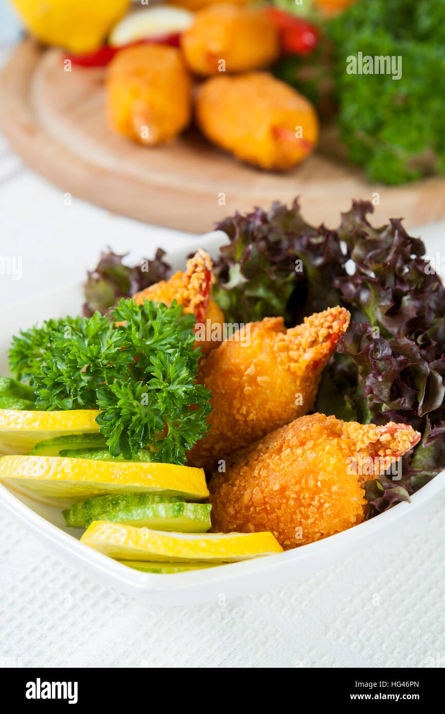 Pinces de crabe frit avec le concombre, le citron, la laitue et le persil on white plate Banque D'Images