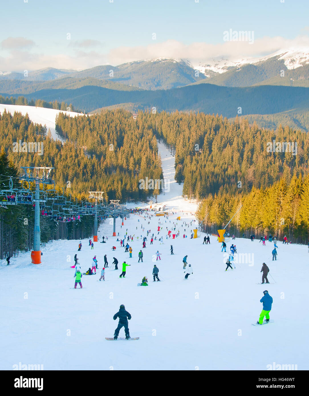 Les gens le ski et le snowboard sur une piste de ski au coucher du soleil Banque D'Images