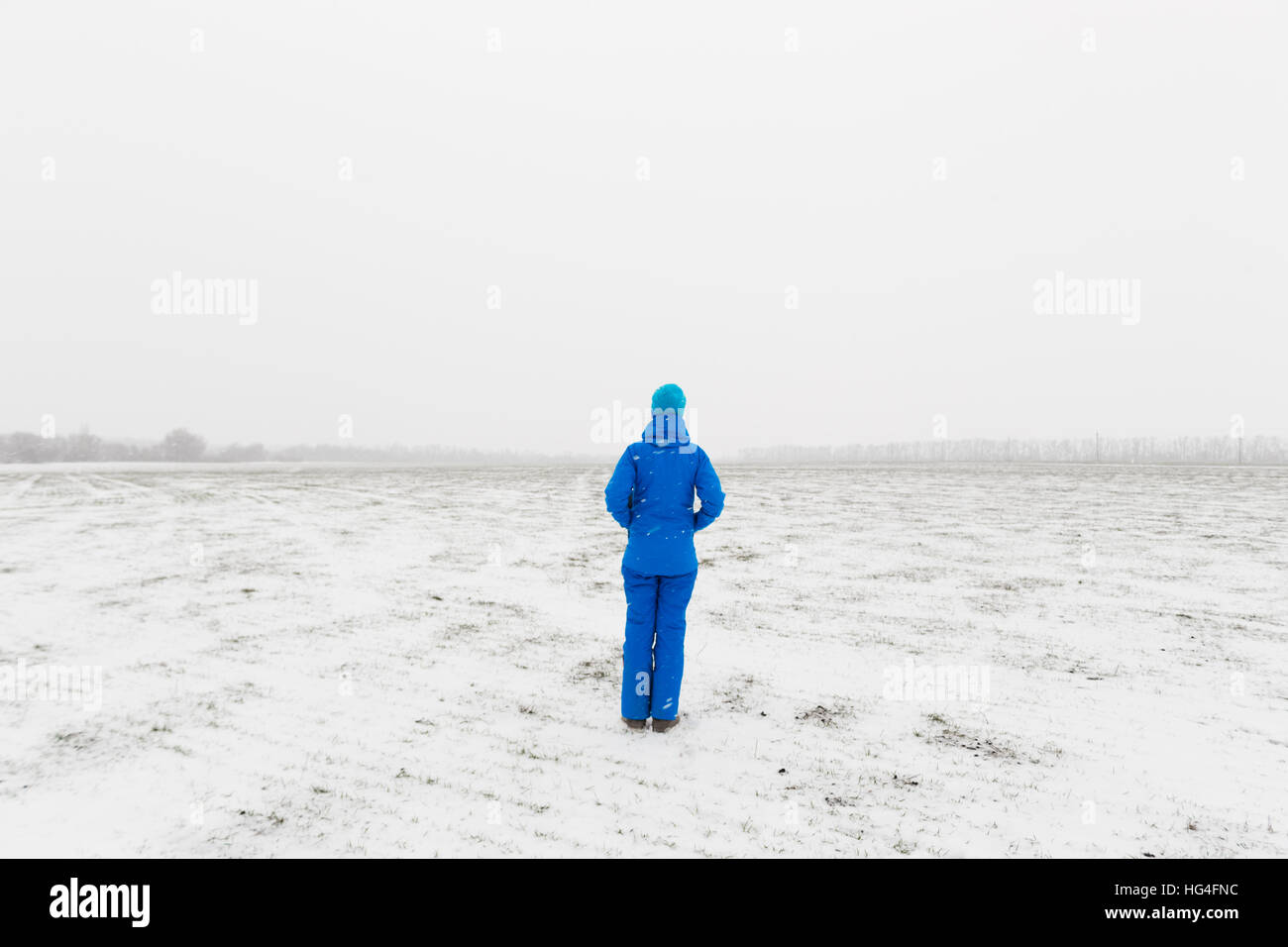 La femme en bleu debout dans un champ neigeux Banque D'Images La femme en bleu debout dans un champ neigeux Banque D'Images