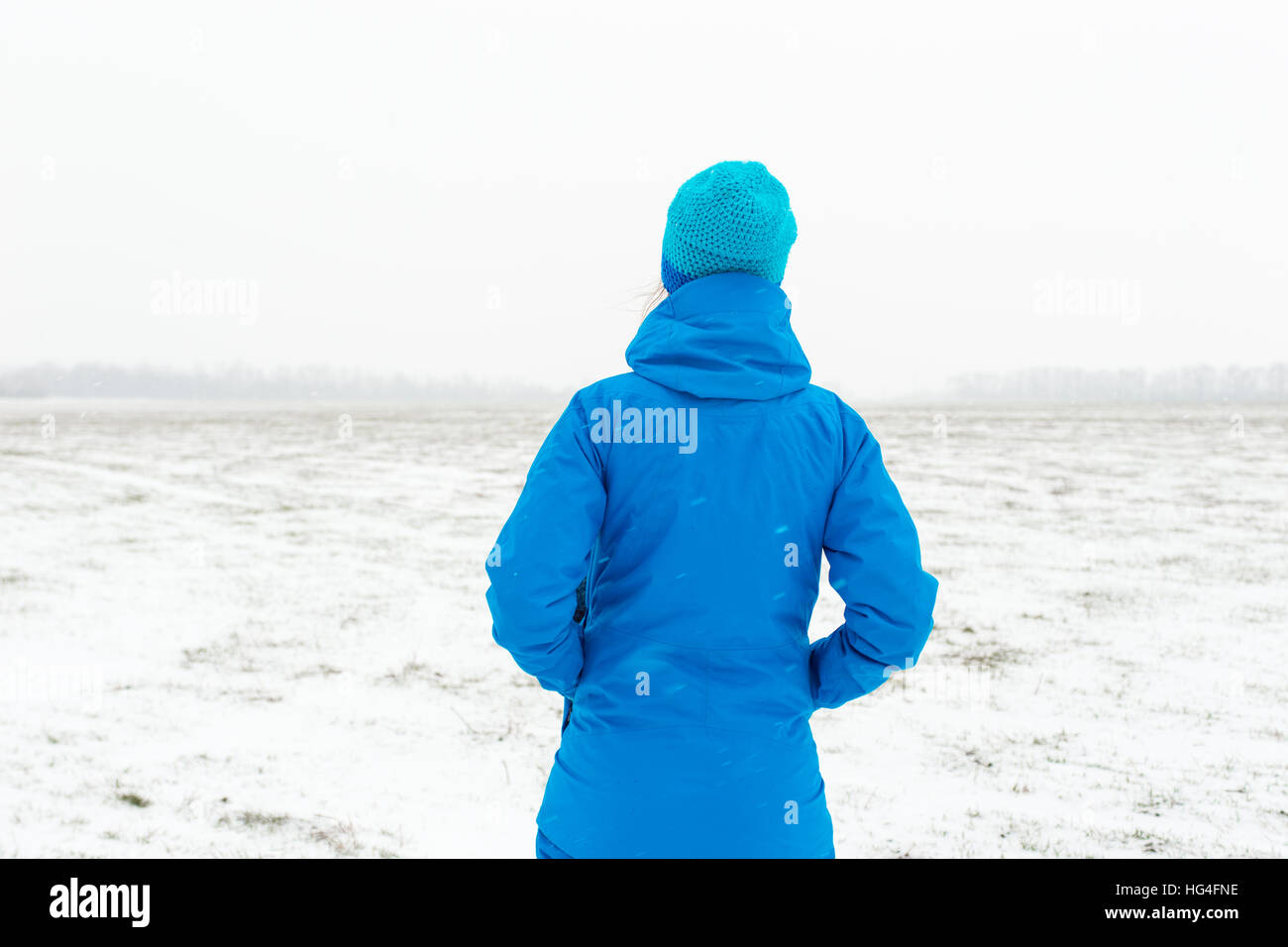 La femme en bleu debout dans un champ neigeux Banque D'Images La femme en bleu debout dans un champ neigeux Banque D'Images