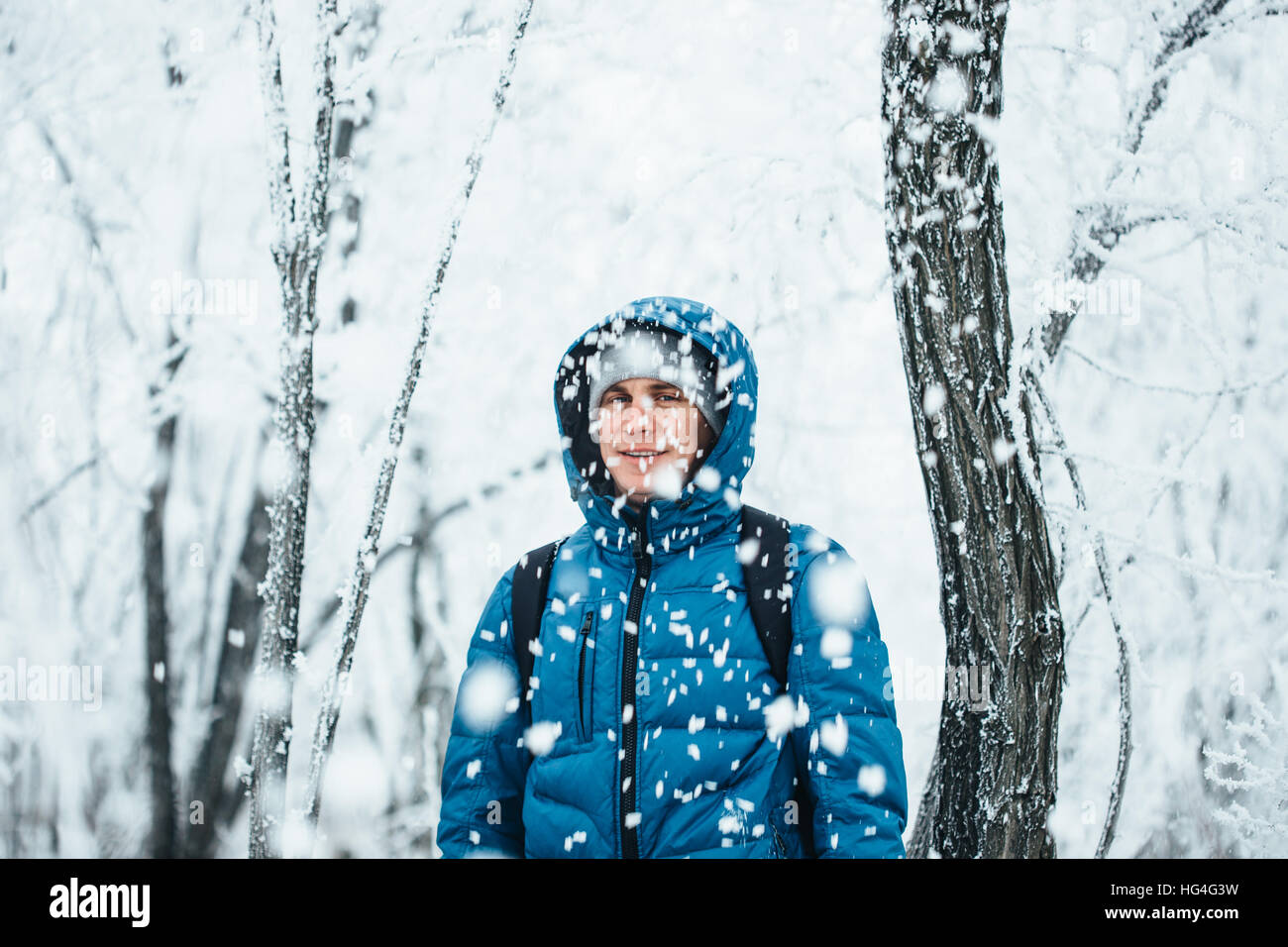 Beau jeune homme debout dans la neige sur fond de forêt enneigée. Banque D'Images Beau jeune homme debout dans la neige sur fond de forêt enneigée. Banque D'Images