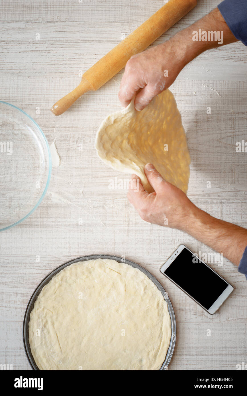 La cuisson de la pâte pour l'homme deux pizzas sur la table verticale Banque D'Images