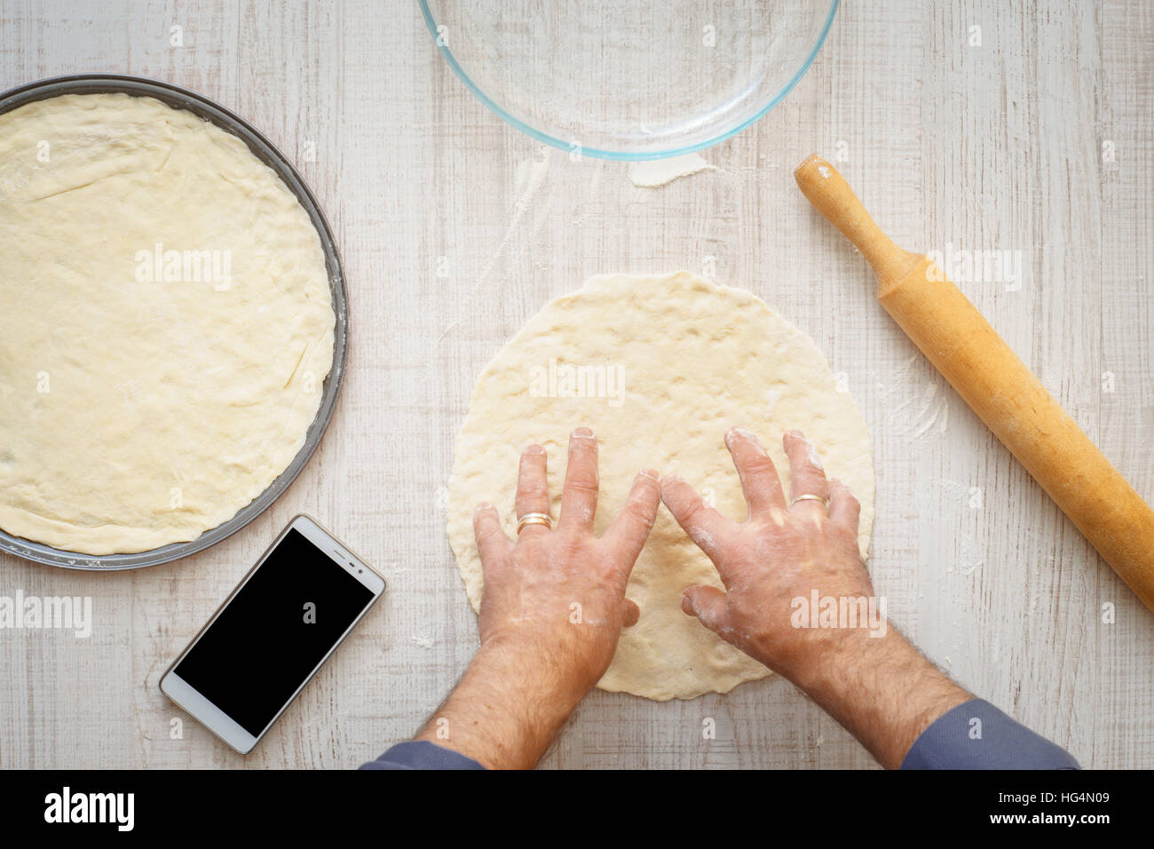 La cuisson de la pâte pour l'homme deux pizzas horizontale sur la table en bois Banque D'Images