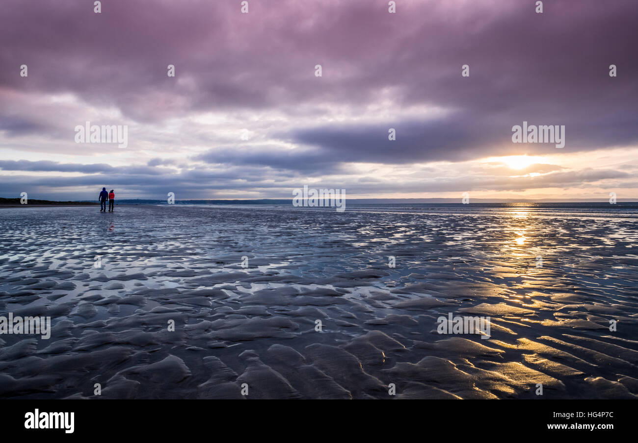 Un couple en train de marcher sur la plage le soir Banque D'Images